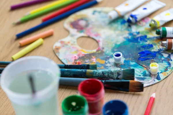 Paleta, pinceles y tubos de pintura sobre la mesa — Foto de Stock