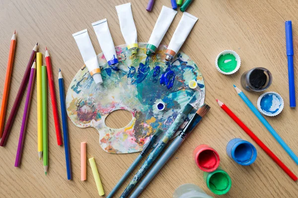 Paleta de cores, escovas e tubos de tinta na mesa — Fotografia de Stock