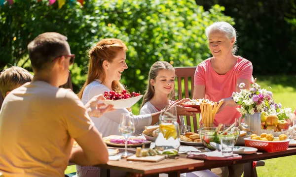 Família feliz ter jantar ou festa no jardim de verão — Fotografia de Stock