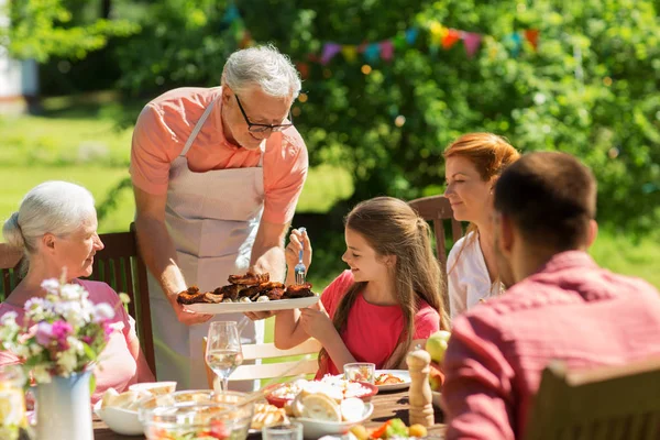 Familie som spiser middag eller griller i sommerhagen – stockfoto