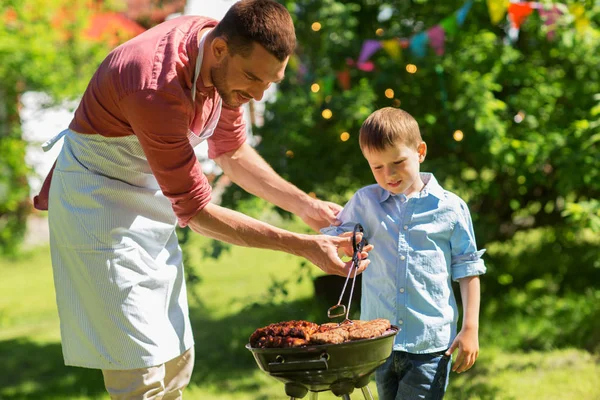 Père et fils cuisiner de la viande sur barbecue grill — Photo