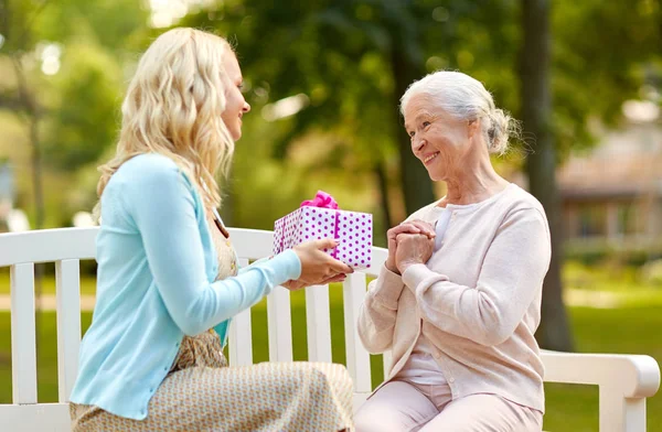 Figlia che dà il regalo a madre più anziana a parco — Foto Stock