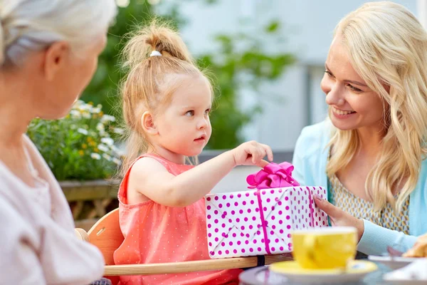 Feliz madre dando regalo a su hija en la cafetería — Foto de Stock