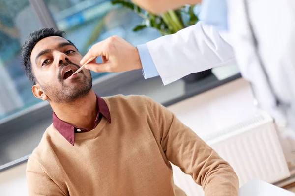 Médico examinando paciente garganta na clínica — Fotografia de Stock