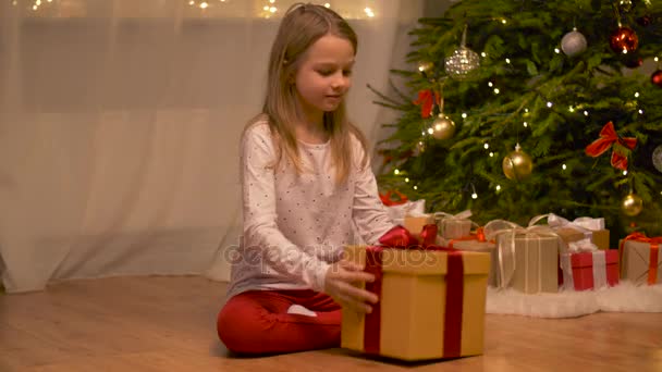 Menina feliz abrindo presente de Natal em casa — Vídeo de Stock