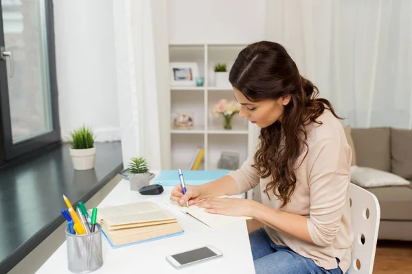 Estudante do sexo feminino com livro de aprendizagem em casa — Fotografia de Stock