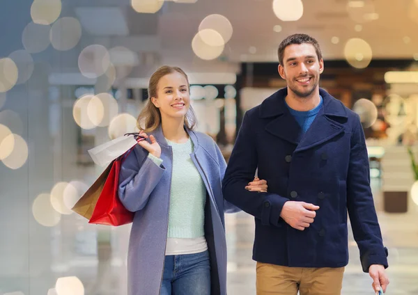 Feliz jovem casal com sacos de compras no shopping — Fotografia de Stock