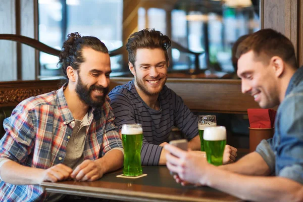 Amigos com smartphone bebendo cerveja verde no pub — Fotografia de Stock