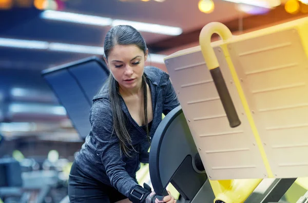 Ung kvinna justera Benpress maskin i gymmet — Stockfoto