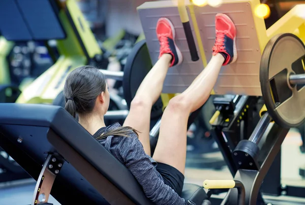 Donna che flette i muscoli sulla pressa per le gambe in palestra — Foto Stock