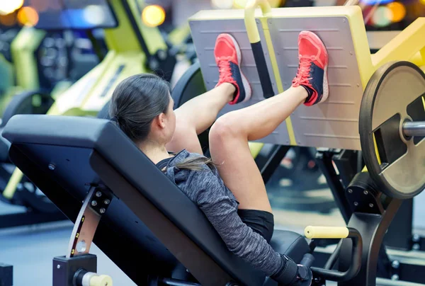 Mujer flexionar los músculos en la máquina de prensa de piernas en el gimnasio — Foto de Stock