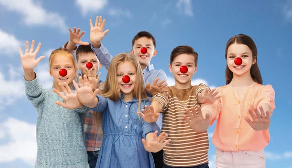 Niños felices saludando las manos en el día de la nariz roja —  Fotos de Stock