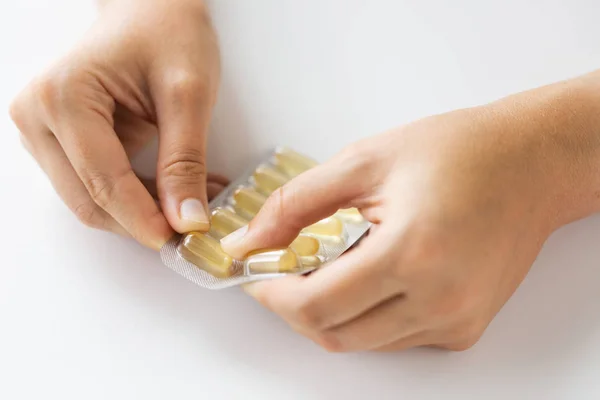 Woman hands opening pack of medicine capsules — Stock Photo, Image
