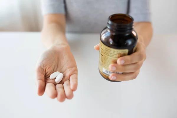 Perto de mãos segurando pílulas de medicina e frasco — Fotografia de Stock