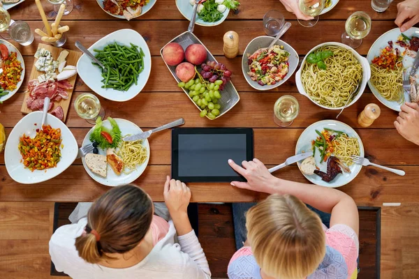 食品の完全なテーブルでタブレット pc を持つ女性 — ストック写真