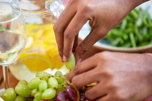 Manos tomando uva del plato con frutas — Foto de Stock