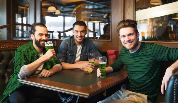 Male friends drinking green beer at bar or pub Stock Photo