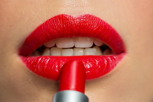 Nahaufnahme einer Frau, die roten Lippenstift auf die Lippen aufträgt Stockbild