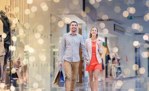 Feliz jovem casal com sacos de compras no shopping — Fotografia de Stock