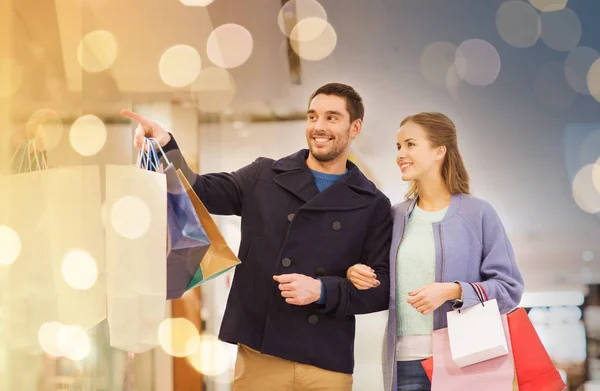 Happy young couple with shopping bags in mall — Stock Photo, Image