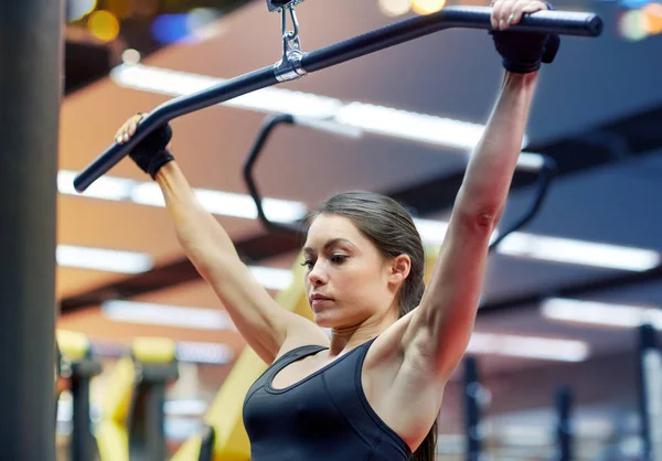 Kvinna som flexar arm muskler på kabel maskin i gymmet — Stockfoto