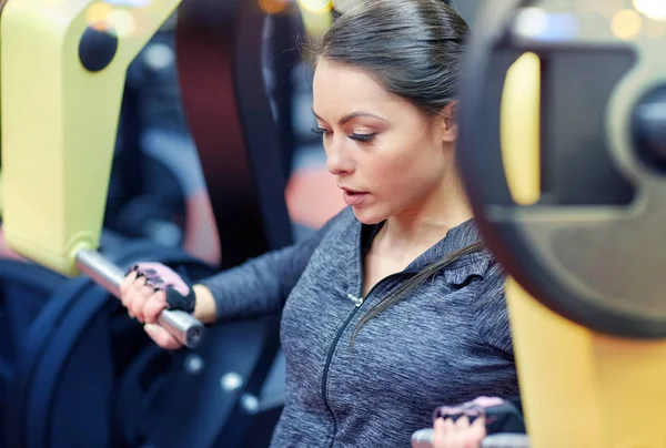 Mujer flexionar los músculos en la máquina de gimnasio de prensa de pecho — Foto de Stock