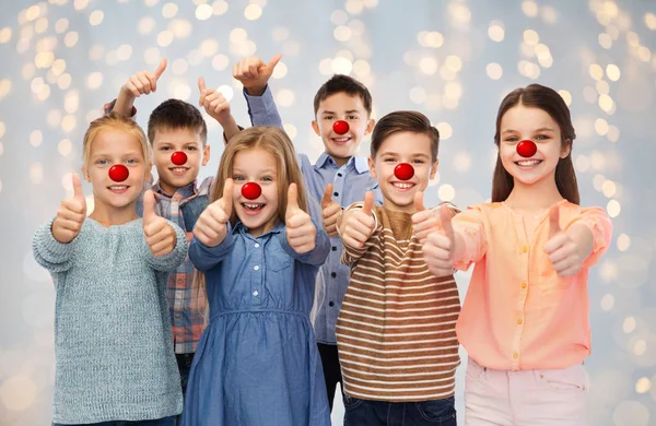Crianças felizes mostrando polegares no dia do nariz vermelho — Fotografia de Stock