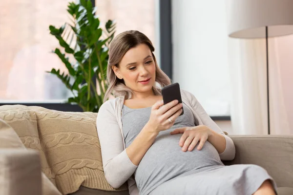 Femme enceinte heureuse avec smartphone à la maison — Photo