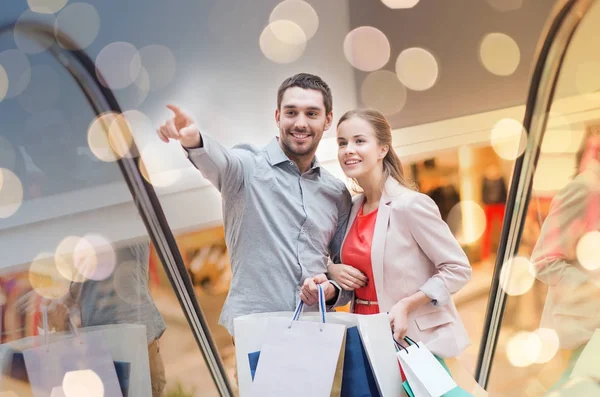 Happy young couple with shopping bags in mall — Stock Photo, Image