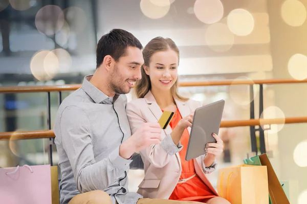 Pareja con tablet pc y bolsas de compras en el centro comercial —  Fotos de Stock