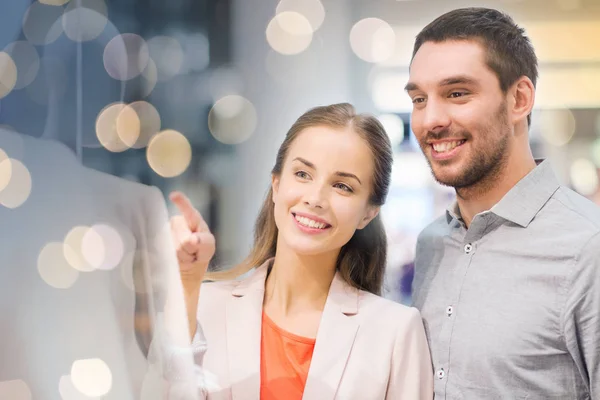 Happy couple pointing finger to shop window — Stock Photo, Image