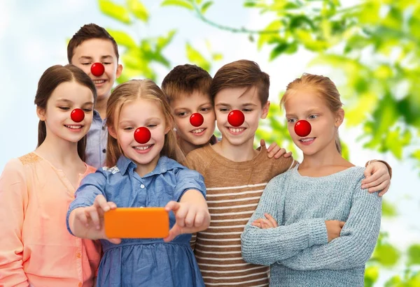 Niños tomando selfie con smartphone en el día de la nariz roja —  Fotos de Stock