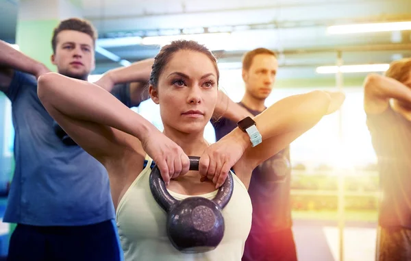 Grupo de personas con pesas haciendo ejercicio en el gimnasio —  Fotos de Stock