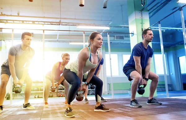 Group of people with kettlebells exercising in gym — Stock Photo, Image