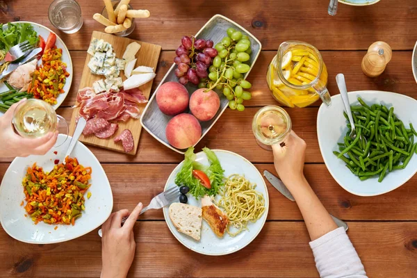Grupo de pessoas comendo à mesa com alimentos — Fotografia de Stock