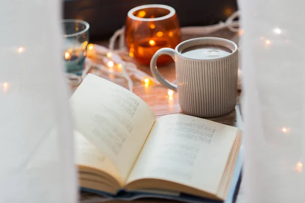 Livro e xícara de café ou chocolate quente na mesa — Fotografia de Stock