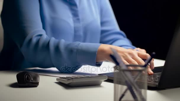 Femme avec calculatrice et ordinateur portable au bureau de nuit — Video
