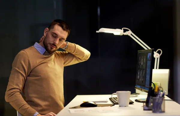 Κουρασμένος άνθρωπος έχοντας πόνος στο λαιμό που εργάζονται στο γραφείο το βράδυ — Φωτογραφία Αρχείου