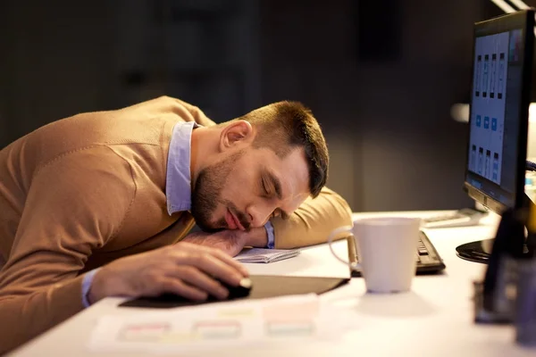 Unavený muž spí na stole v kanceláři noci — Stock fotografie
