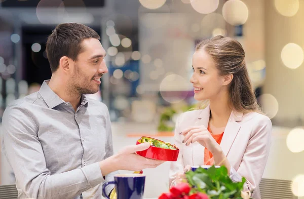 Gelukkige paar met heden en bloemen in winkelcentrum — Stockfoto