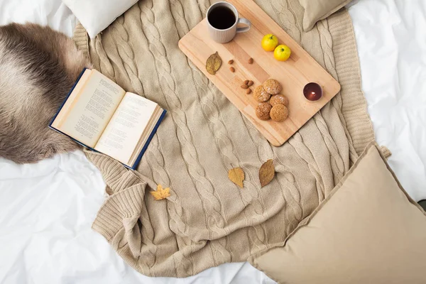Galletas, té de limón, libro y hojas en la cama — Foto de Stock