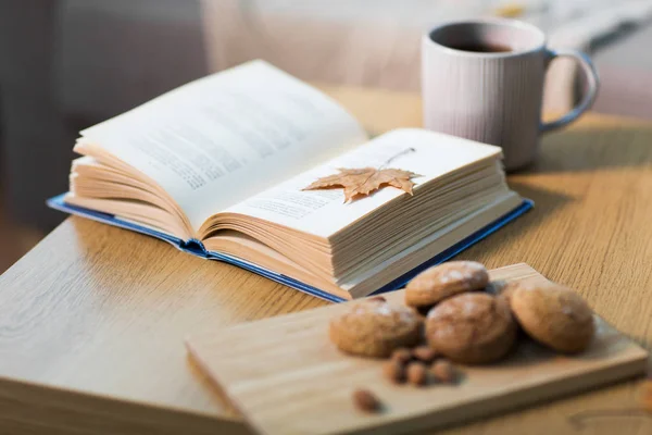 Książki z jesiennych liści, pliki cookie i herbata na stole — Zdjęcie stockowe