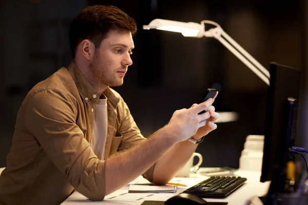 Людина зі смартфоном працює пізно в нічному офісі — стокове фото