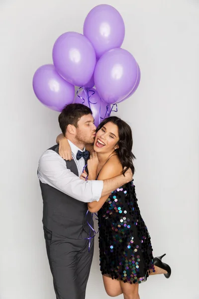 Casal feliz com balões violeta beijando na festa — Fotografia de Stock