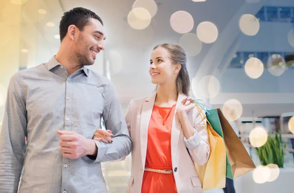 Happy young couple with shopping bags in mall — Stock Photo, Image