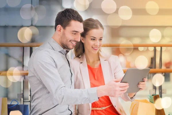 Casal com tablet pc e sacos de compras no shopping — Fotografia de Stock