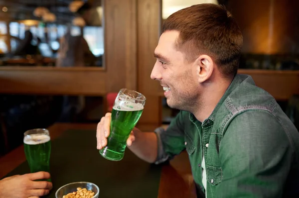 Человек пьет зеленое пиво в баре или пабе — стоковое фото