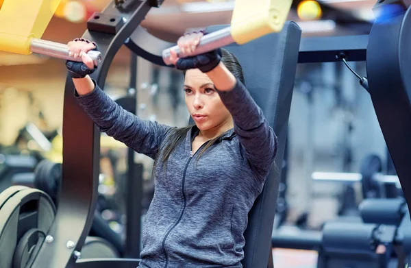 Kvinnan böjning muskler på bröst tryck gym maskin — Stockfoto