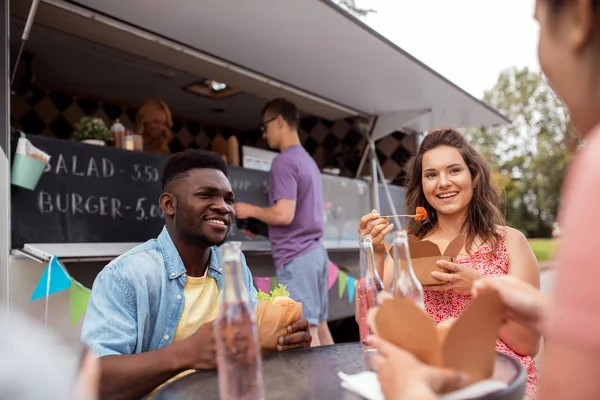 Amici felici con bevande mangiare al camion cibo — Foto Stock