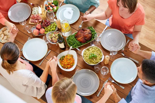 Group of people at table praying before meal — Stock Photo, Image